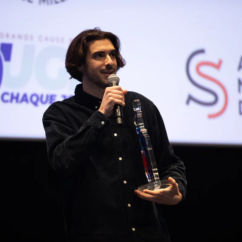 Thomas Gonçalves, micro en main, tient son trophée sur la scène du festival Les Sportives en Lumière.